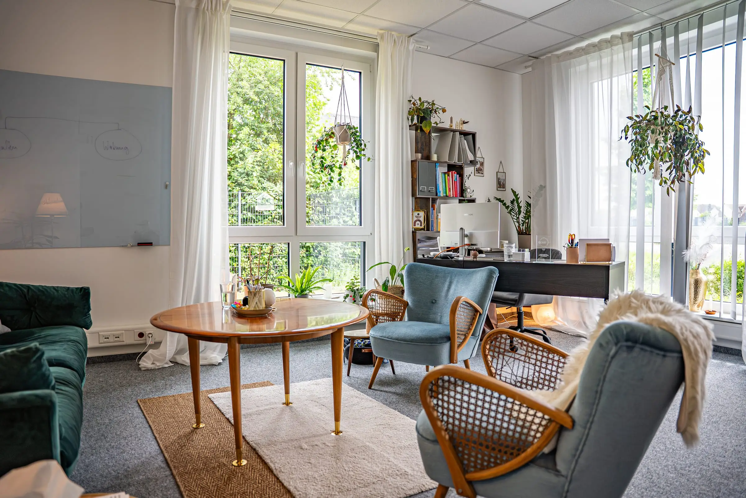 Loungebereich der Praxis JUNA mit Sofa, Sesseln und rundem Tisch